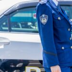 パトカー横に立つ警察官