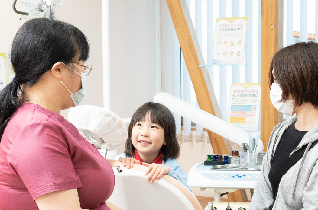 お子さまとお母さんと話す歯科医師本田
